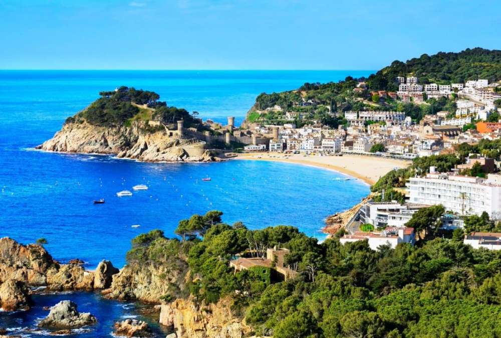 A Spanish coastline. With hotels and resorts to the right and the sea to the left.