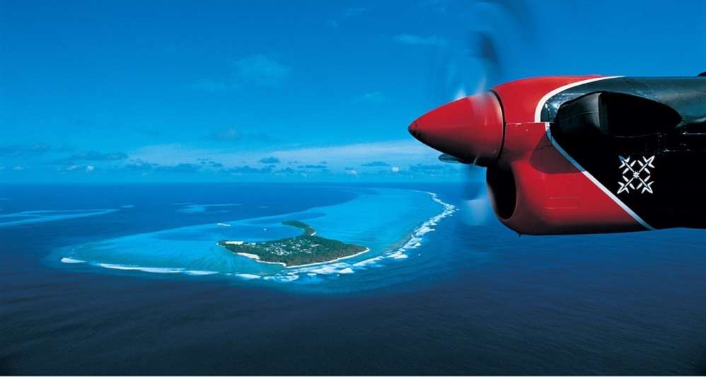 A plane flying over a small Maldives island.