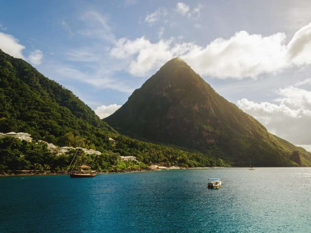 The Pitons are in the distance while three boats are in the sea.